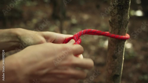 Man ties a safety rope around the harness before top rope climbing photo