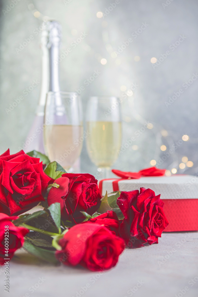 Champagne and red roses with bokeh. Valentine's setting with red roses and present Champagne and red roses with bokeh. Valentine's setting with red roses and present