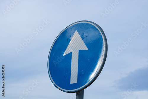 Proceed straight only direction sign on cloudy sky background.