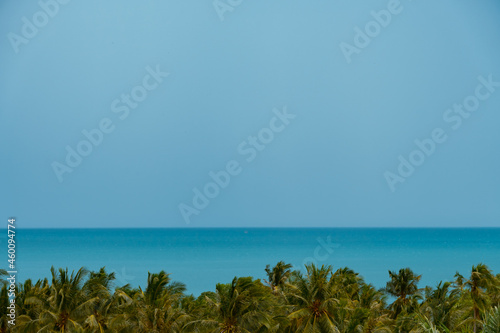 Dramatic clouds over turquoise sea. Palm trees in the foreground.