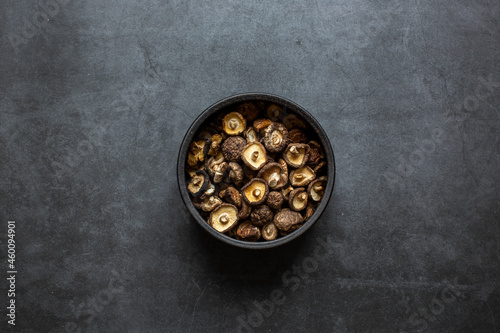 Dried Shiitake Mushrooms in bowl on dark grey background. © litchima