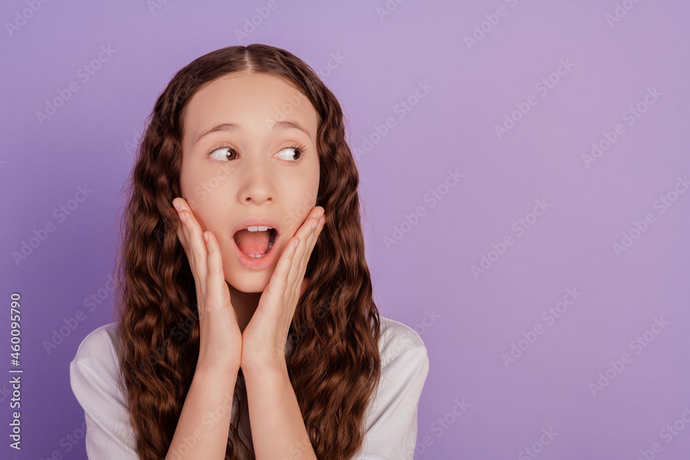 Portrait of frightened child touch hands cheeks look empty space isolated over purple background Portrait of frightened child touch hands cheeks look empty space isolated over purple background