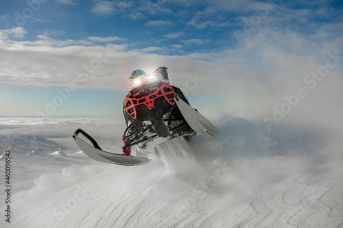 snowmobilers - extreme. the concept of advertising mountain and professional snowmobile driving. a bright pilot and a beautiful jump with a turn on a snowmobile