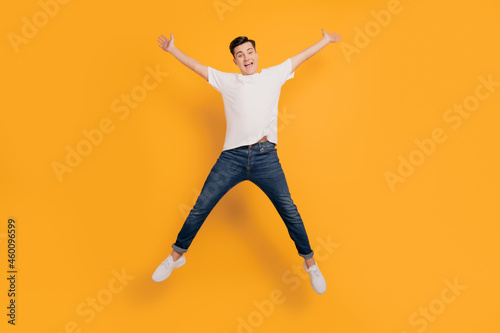 Portrait of funky astonished guy jump make star shape have fun on yellow background
