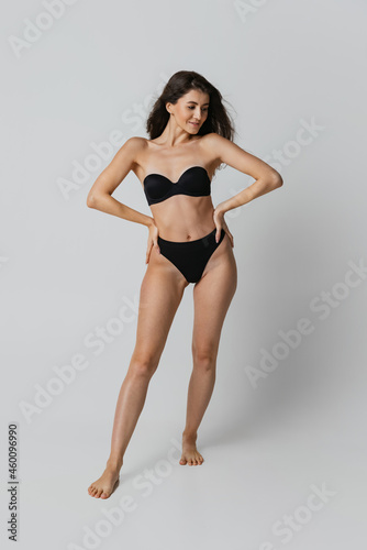 Portrait of young beautiful slim woman in lingerie posing isolated over light gray studio background. Natural beauty concept.