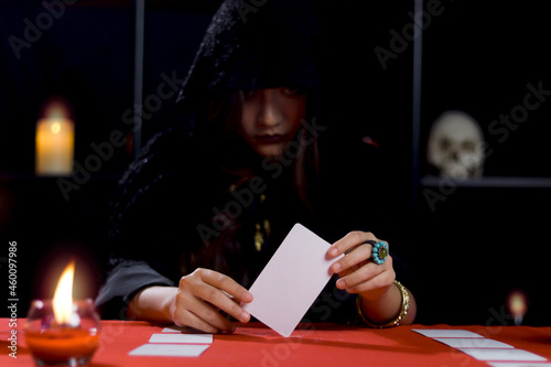 Obraz na plátně Dark witch in black hood holding magical card, mysterious magnificent beautiful