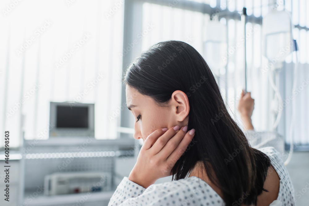 sick woman adjusting hair while holding hand on drop counter with intravenous therapy bottles sick woman adjusting hair while holding hand on drop counter with intravenous therapy bottles