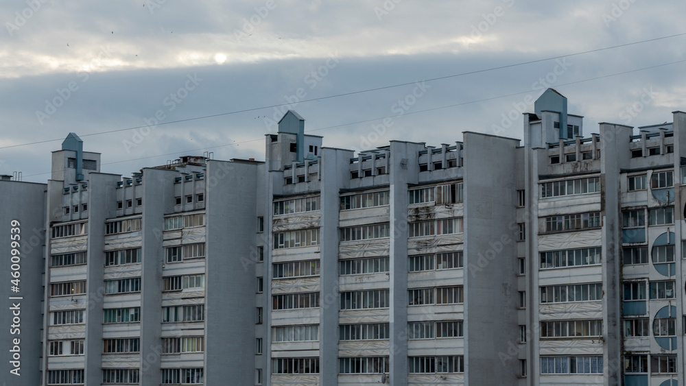 Bottom view of a multi-storey panel residential building on dramatic sky background. City life view.