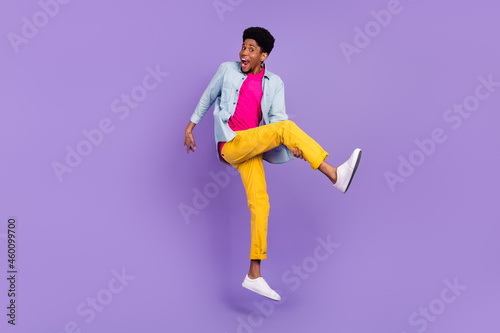 Photo of inspired guy jump hold leg imagine play guitar wear blue shirt pants shoes isolated purple color background