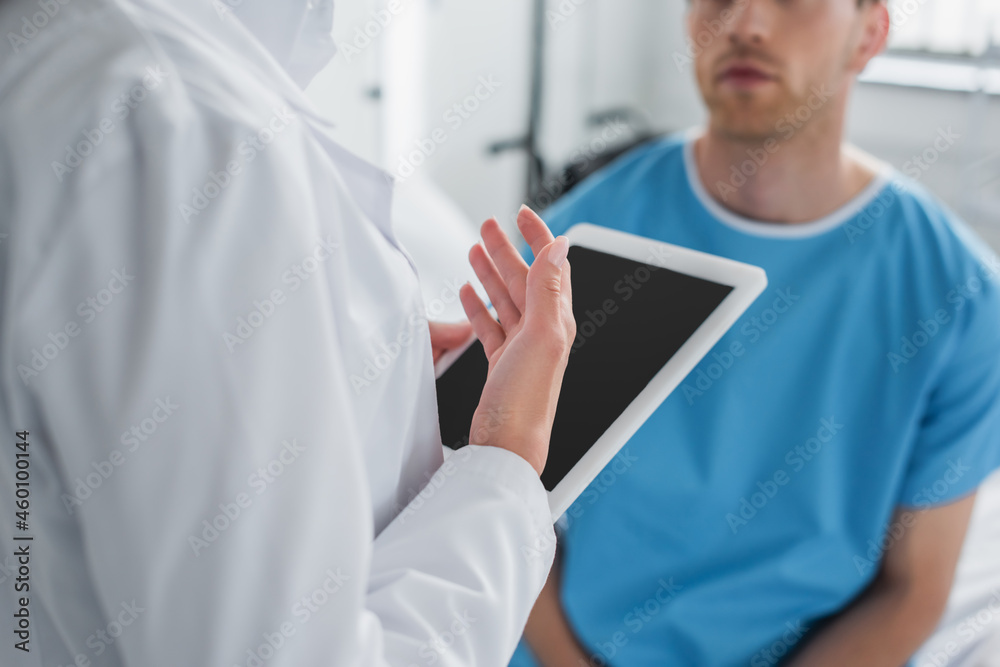 cropped view of doctor in white coat holding digital tablet near patient