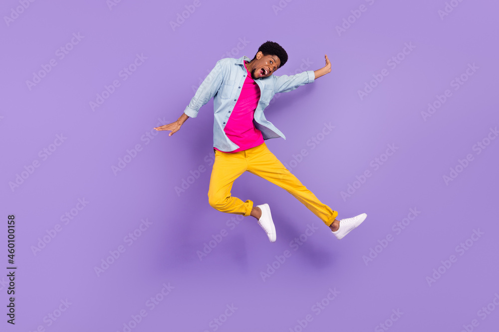 Photo of sportive crazy carefree guy jump excited face wear blue shirt pants sneakers isolated purple color background