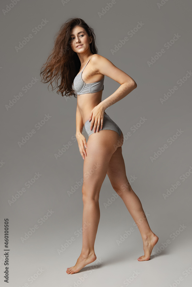 Portrait of young beautiful slim woman in lingerie posing isolated over light gray studio background. Natural beauty concept.