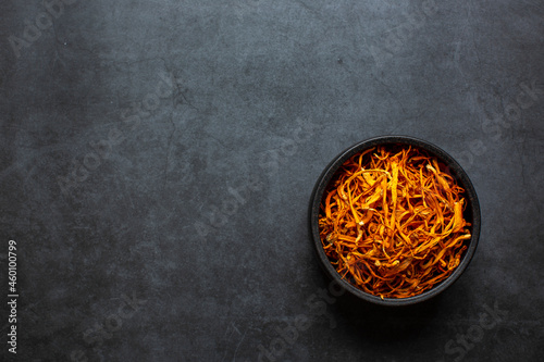 Dried cordyceps militaris mushroom in bowl on dark grey background. Cordyceps flower photo