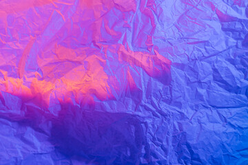 Abstract background with crumpled paper in neon gradient. Vivid blue, pink and orange colors