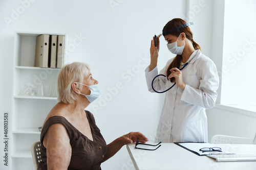 elderly woman wearing a medical mask on examination by a nurse health diagnostics