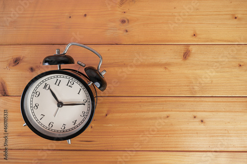 Top view of black retro alarm clock put on wooden table