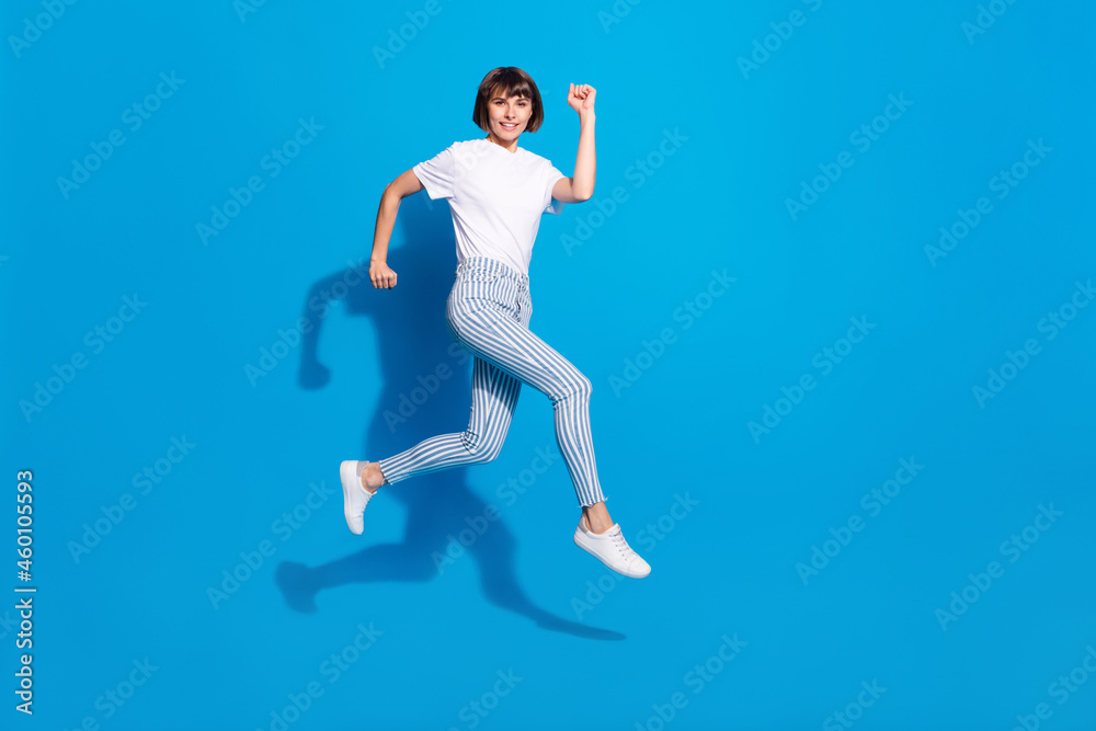 Photo of pretty charming young woman dressed casual clothes jumping running fast smiling isolated blue color background