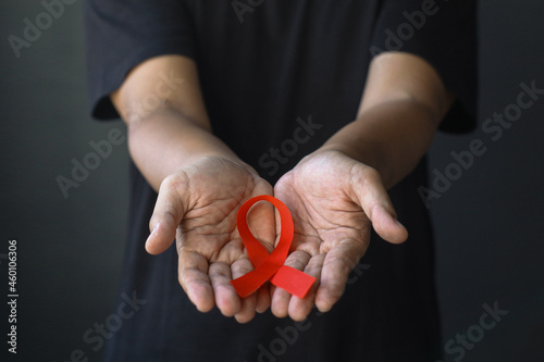 World Aids Day and World Diabetes Day with male hands holding red AIDS awareness ribbon. Healthcare and medicine concept. 