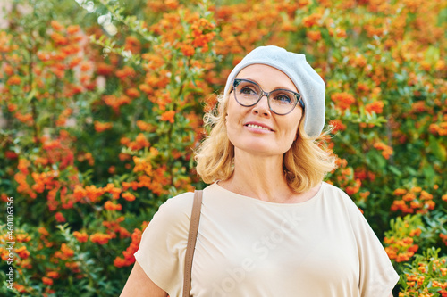 Outdoor portrait of happy middle age woman posing next to bright orange scarlet firethorn berries (Pyracantha coccinea) photo