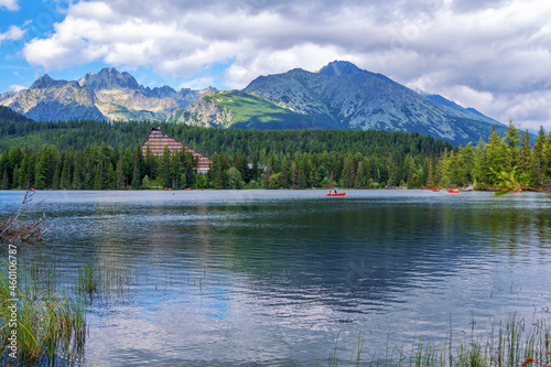Beautiful summer landscape of High Tatras  Slovakia     Strebske Lake  tourists  enjoying boats riding  lush forest  mountains and white clouds on the sky