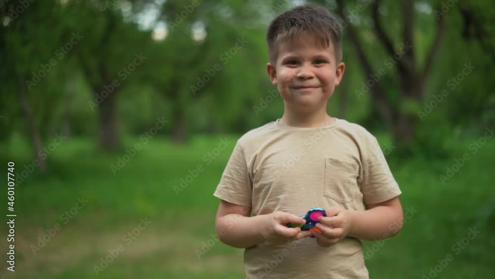 Child is Having Fun and Playing an Anti-Atress Toy. Kid is Playing Trendy Popular Game Toy Pop It in Garden. High quality 4k footage Child is Having Fun and Playing an Anti-Atress Toy. Kid is Playing Trendy Popular Game Toy Pop It in Garden. High quality 4k footage