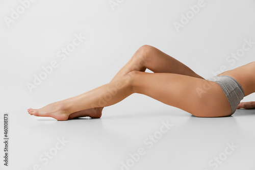 Beautiful slender female hips and legs isolated on gray studio background. Natural beauty, spa, anti-cellulite treatments concept.
