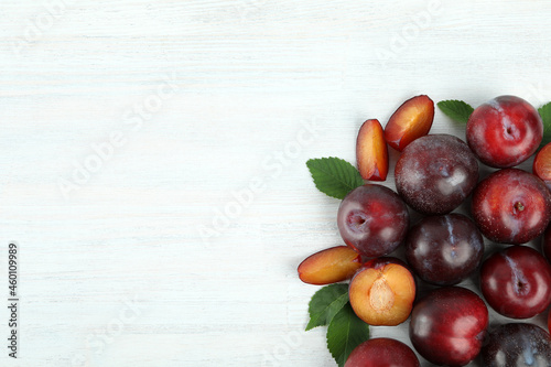 Flat lay composition with plums on white wooden background