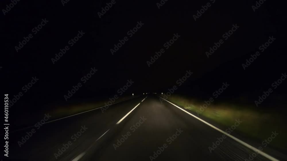 point of view hyper lapse of driving along Iceland roads at night. the car is speeding along highway with the headlights being the only way making the road visible