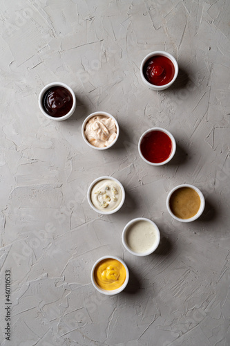 A lot of different sauces and dips on stone grey background, fashionable ad photo