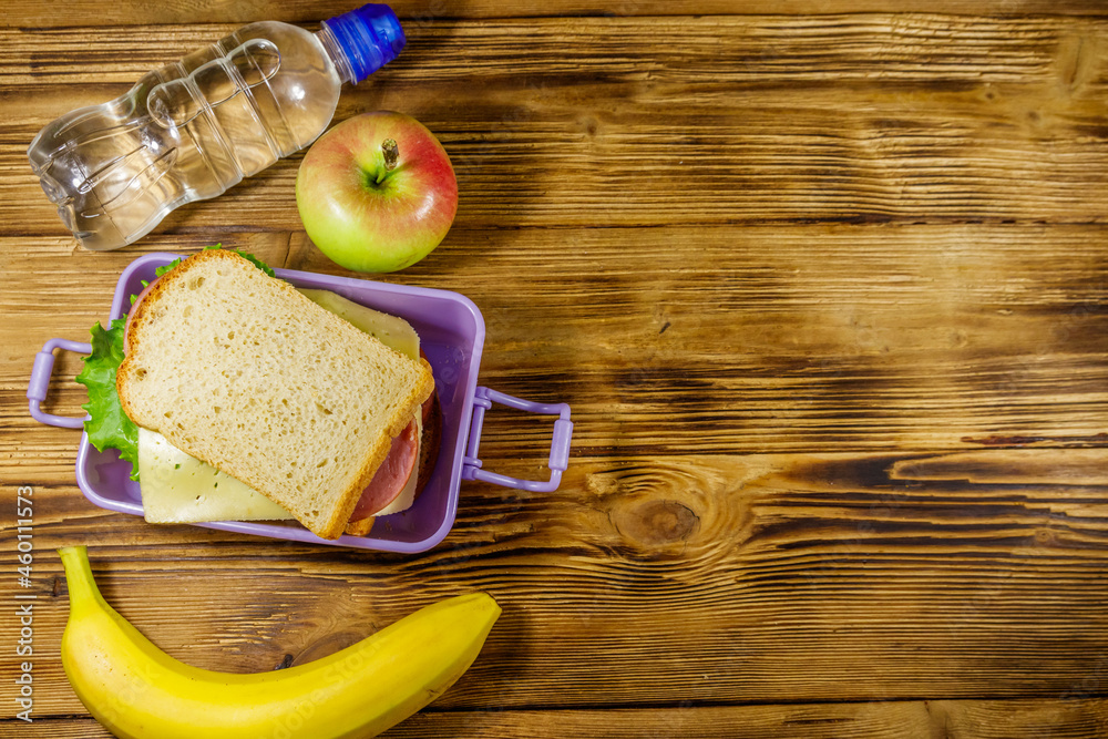Lunch box with sandwiches, bottle of water, banana and apple on a wooden table. Top view, copy space Lunch box with sandwiches, bottle of water, banana and apple on a wooden table. Top view, copy space