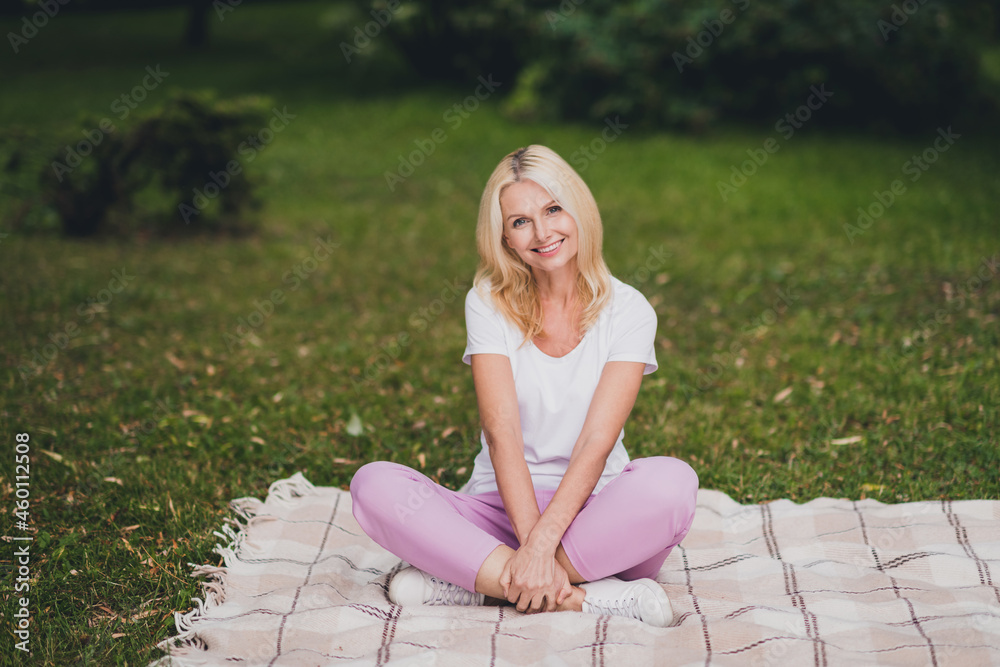 Full length photo of mature sweet blond lady sit wear t-shirt trousers sneakers in park alone