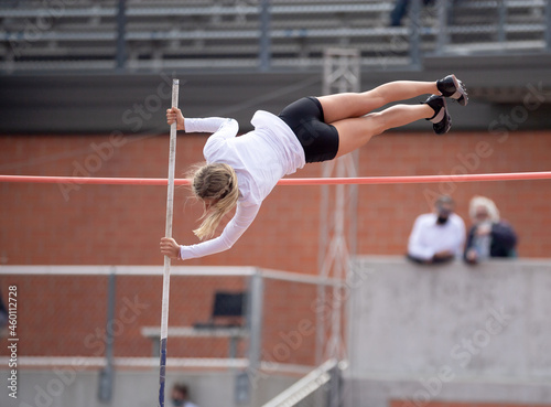 High School girls competing in pole vault at a track and field meet photo