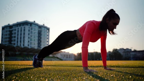 Fitness girl doing pushups exercise at workout on track. Sport woman doing push ups. Athletic woman training hard at stadium. Portrait of fit girl having outdoor workout.
