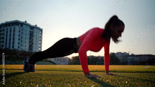 Fitness girl doing pushups exercise at workout on track. Sport woman doing push ups. Athletic woman training hard at stadium. Portrait of fit girl having outdoor workout.