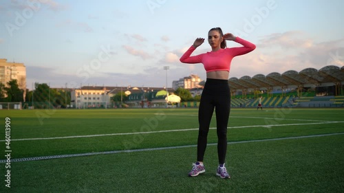 Fitness woman in sportswear doing various exercises on sports mat, on green football field with white markings, at stadium. Outdoor sports. online training. hot summer day. healthy lifestyle concept