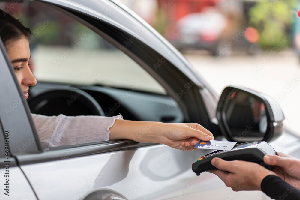 woman driving a car to fill up gas at a gas station uses a credit card to pay for gas, convenient to pay. 