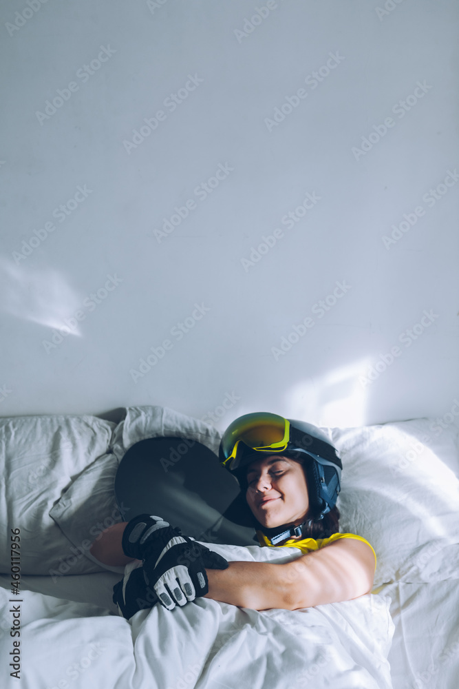 woman sleeping in bed with snowboard dreaming about ski at snow mountains