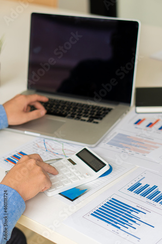 Vertical picture of business people analyzes and discusses and brainstorms data, charts, financial reports in the conceptual work consulting office. An accountant working on a desk using a calculator 