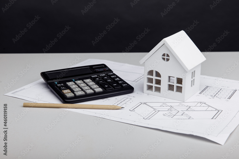 White house and calculator on drawing. House building costs concept White house and calculator on drawing. House building costs concept