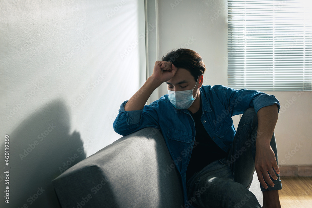 Fototapeta premium An upset health problem Asian patient man wearing a face mask at home or hospital alone sad and waiting for a doctor. Hospital and Health care during Coronavirus or Covid-19 quarantine concept