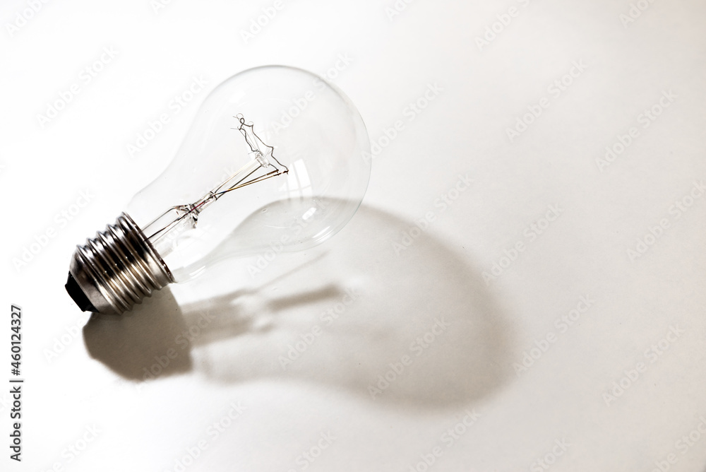 Lampadina spenta, su superficie bianca, che proietta le propria ombre sulla superficie bianca. Lampadina spenta, su superficie bianca, che proietta le propria ombre sulla superficie bianca.