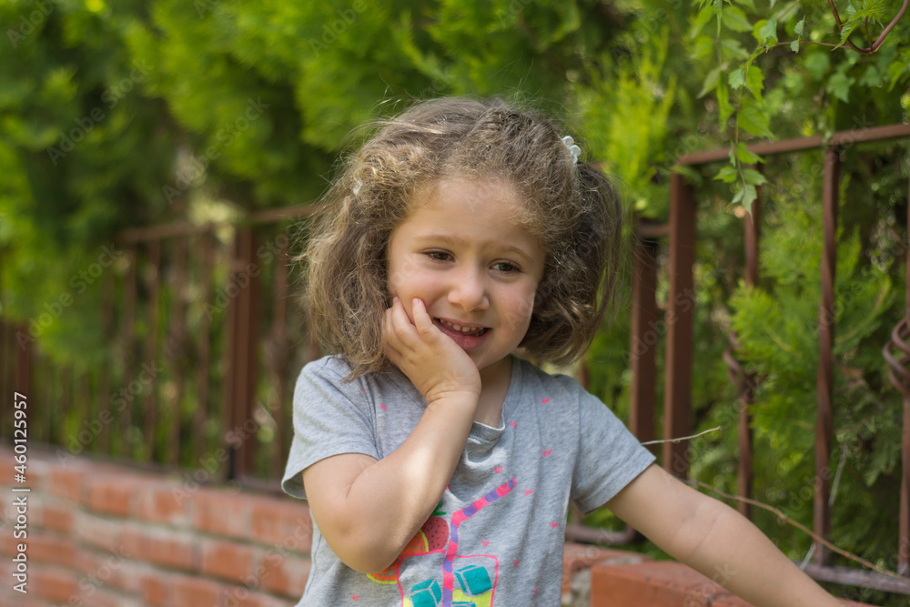 little girl smiling cheerfully in front of the red brick wall in the garden little girl smiling cheerfully in front of the red brick wall in the garden