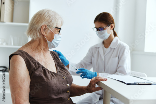 doctor with a syringe vaccination of an elderly woman immunity protection covid passport