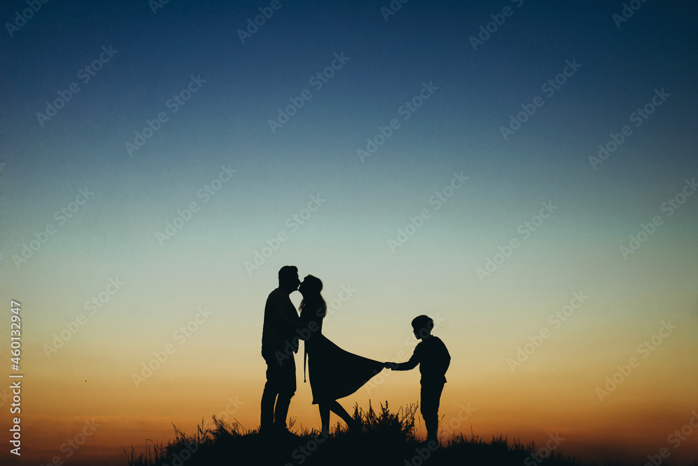 silhouettes of mom and dad against the sky, parents kissing, and the boy pulls mom by the hem of the dress