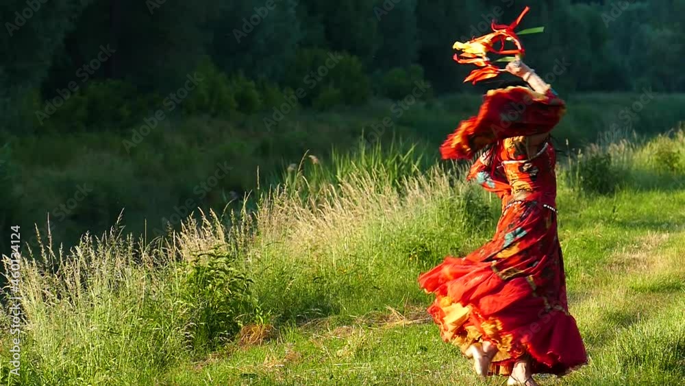 Gypsy artist in a red dress performs a dance and beats a tambourine against a background of green mountains, slow motion. Clothes for gypsy dance. Happy woman. Positive mood. Carefree girl dancing. Gypsy artist in a red dress performs a dance and beats a tambourine against a background of green mountains, slow motion. Clothes for gypsy dance. Happy woman. Positive mood. Carefree girl dancing.