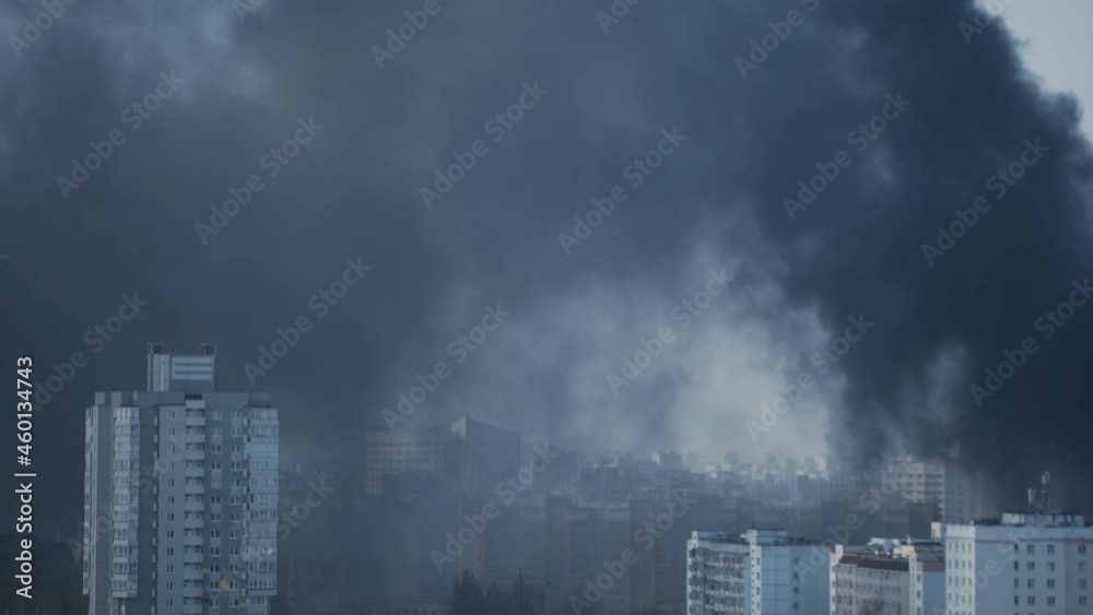Dense black smoke from fires and explosions blankets high-rise apartment buildings in the city. Environmental disaster, air pollution in the metropolis Dense black smoke from fires and explosions blankets high-rise apartment buildings in the city. Environmental disaster, air pollution in the metropolis