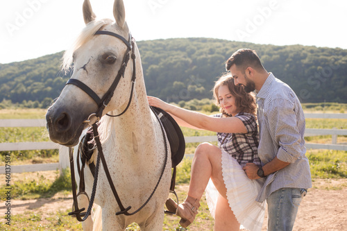 The young man helps his wife to get on a horse