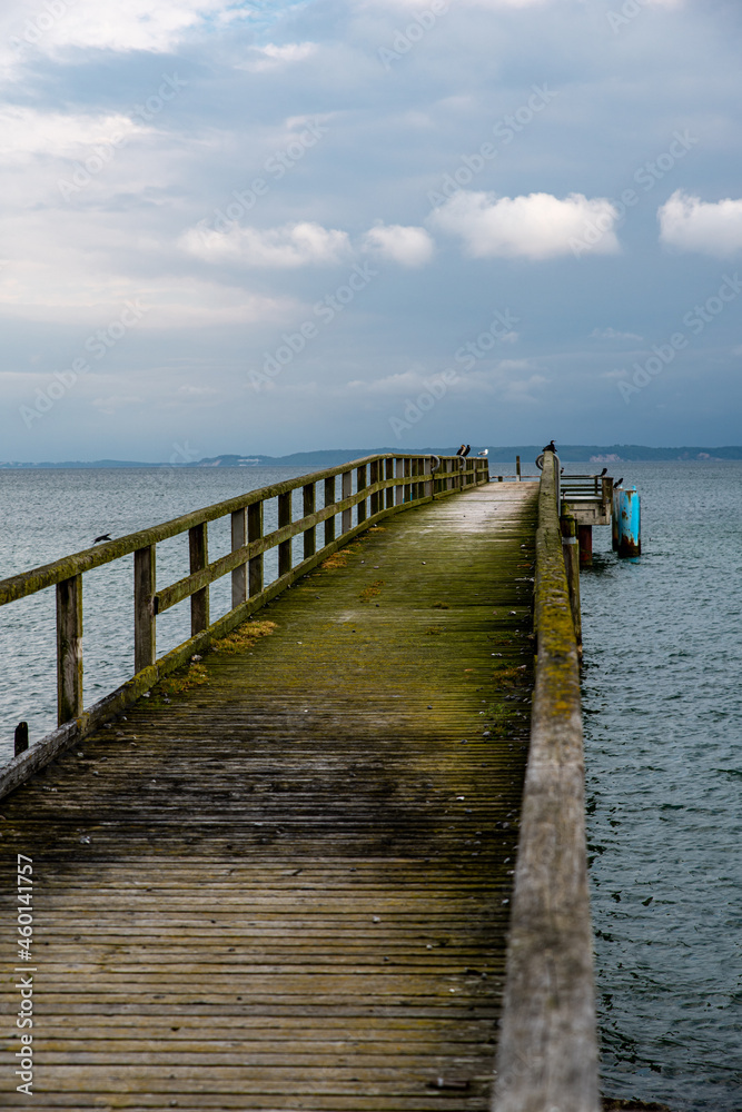 View along an old jetty onto the Baltic Sea and a dramatic cloudy sky 