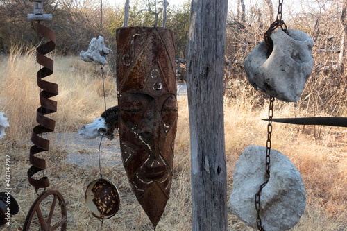 Close up of a rusty metal african mask  with old metal and animal skulls hanging beside it. photo