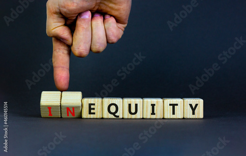 Inequity or equity symbol. Businessman turns wooden cubes and changes the word inequity to equity. Business and inequity or equity concept. Beautiful grey background, copy space.